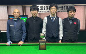 The semi-finalists in the 2023 All-Japan Snooker Championship pose for a photo by the snooker table and stand behind the trophy.