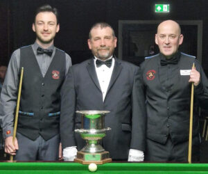 Darryl Hill and Tom Miller stand either side of the referee and trophy for the 2023 Isle of Man Snooker Championship Final.