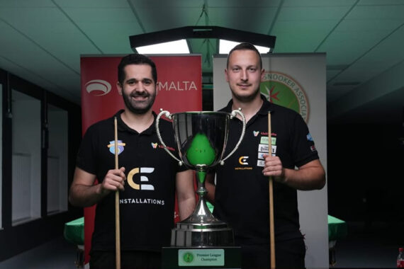 Aaron Busuttil and Brian Cini pose with cues in front of the big Maltese Snooker Championship trophy.