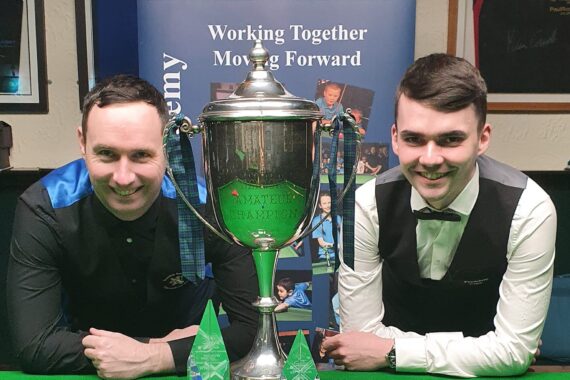 Michael Collumb and Chris Totten lean on the table either side of the Scottish championship trophies.