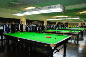 Players in waistcoats line up standing at the top of the tables in the 2023 Pan American Snooker Championship arena.