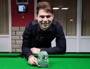 Aleš Herout leans on a snooker table and poses with his trophy.