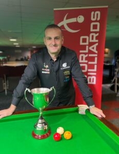 David Causier poses with The Philip Brooke Trophy in front of him on the table.