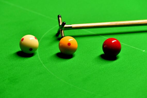 Three English billiards balls next to each other on the table by a rest.