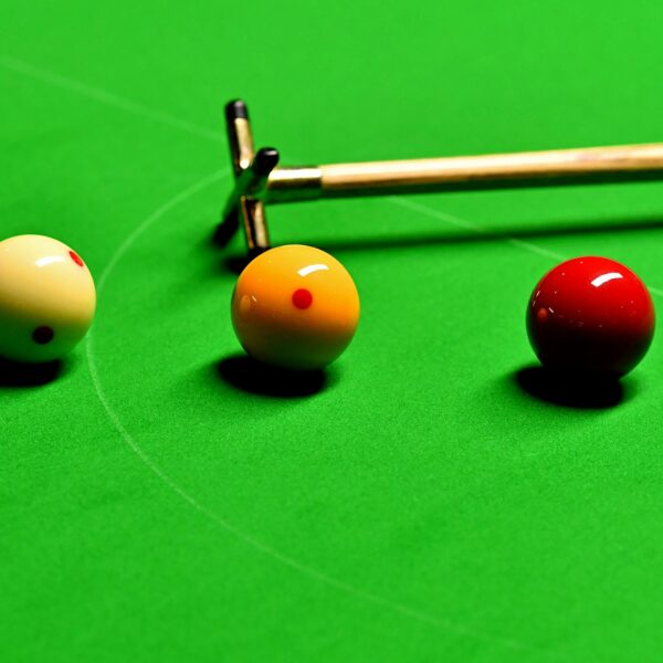 Three English billiards balls next to each other on the table by a rest.