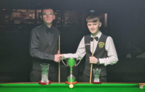Joel Connolly and Robbie McGuigan shake hands by the table and in front of the trophies for the 2023 Northern Ireland Under-21 Snooker Championship.