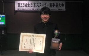 Keishin Kamahashi holds the trophy and a certificate.